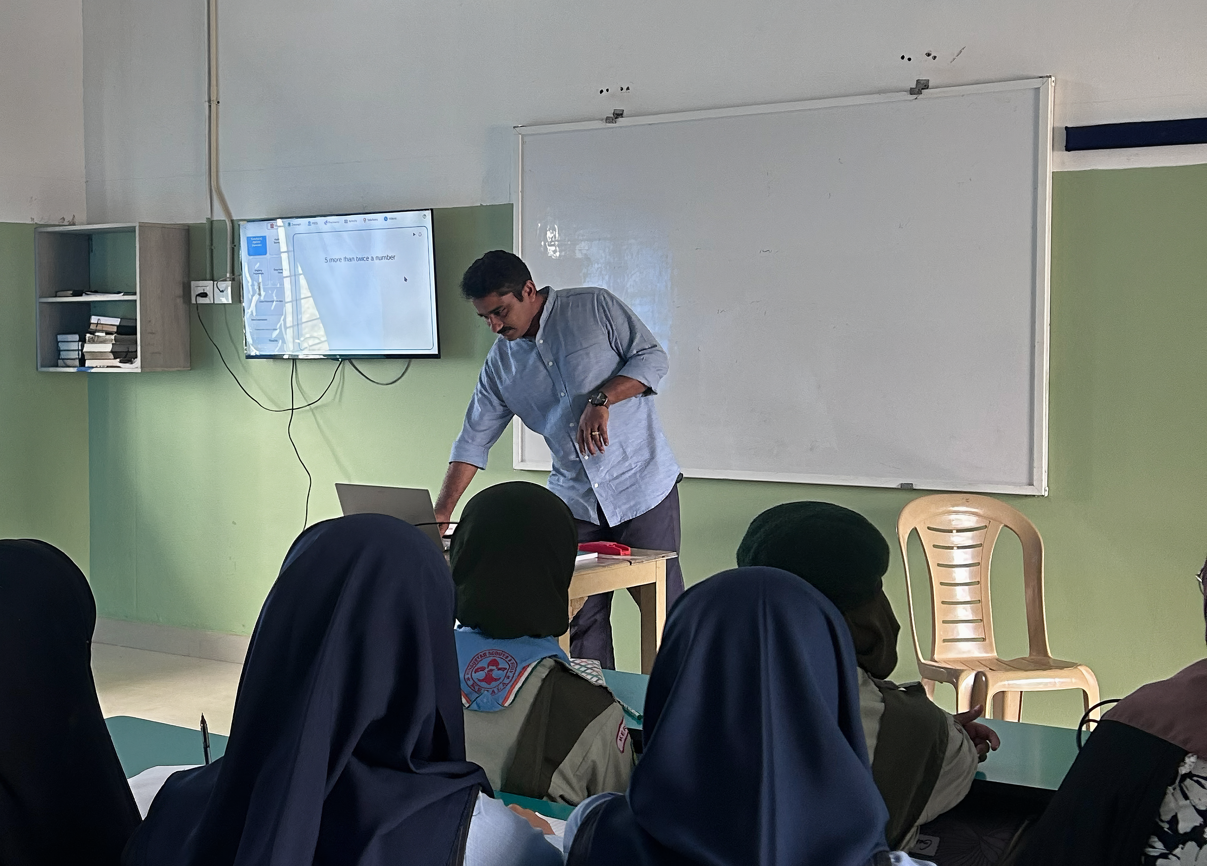 Instructor teaching students with laptop and digital display
